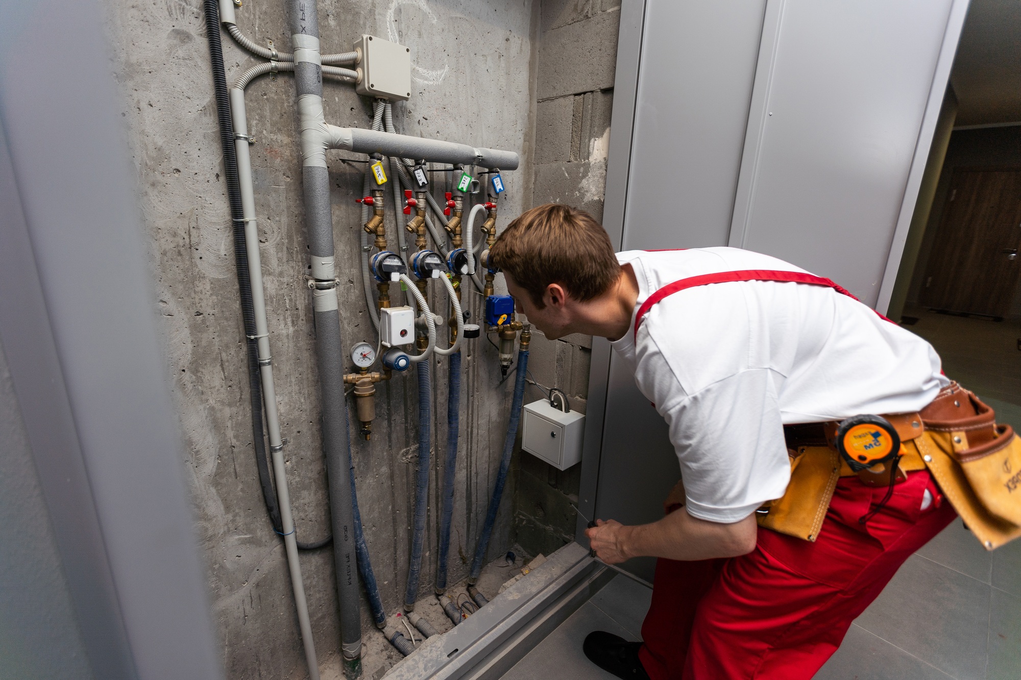 Male plumber fixing water meter with adjustable wrench.