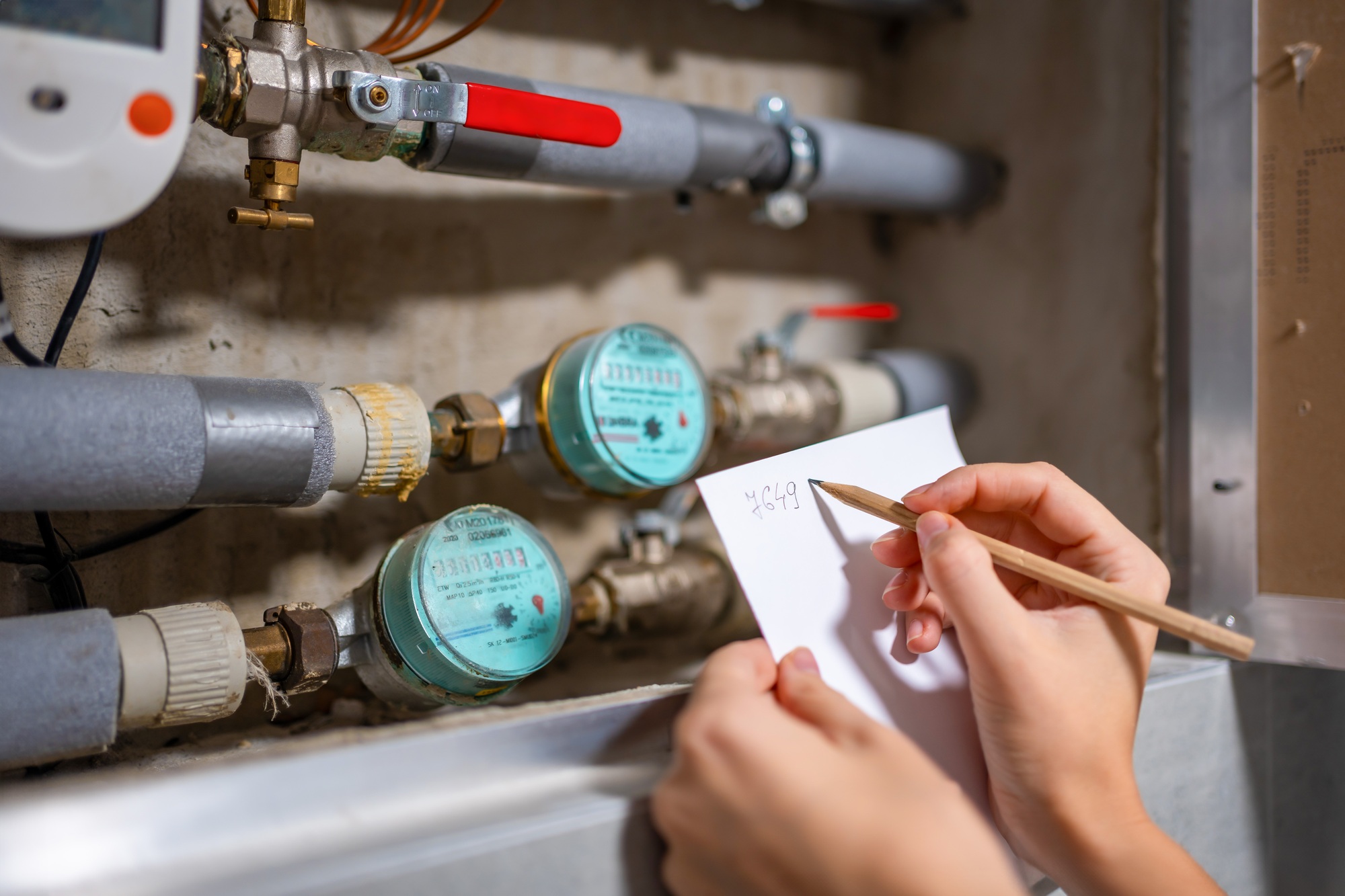 Woman recording meter readings, water meters of cold and hot water, water consumption in real